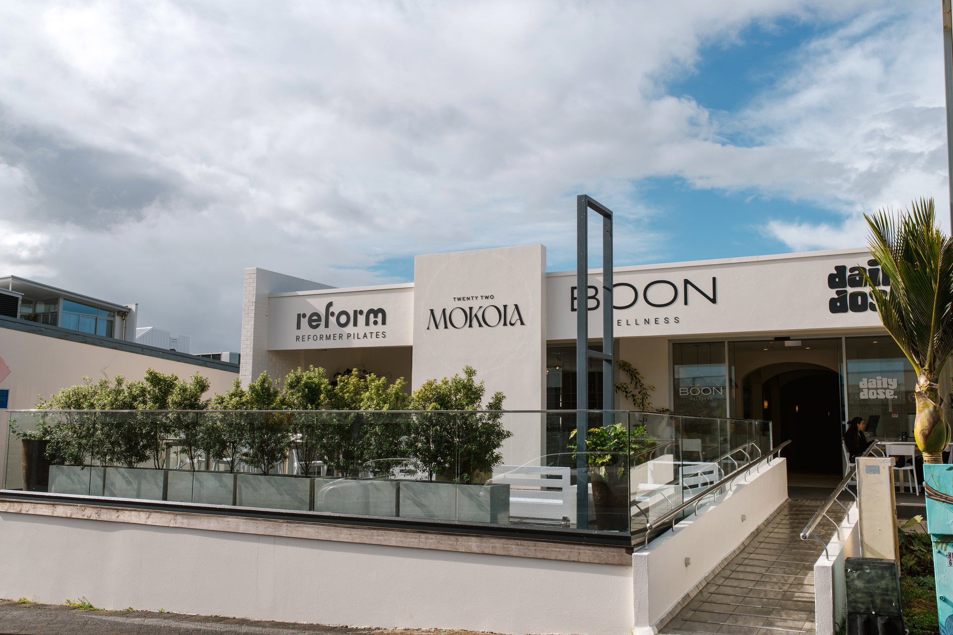 The Twenty Two Mokoia facade on Mokoia Road, with Reform, Boon Wellness and Daily Dose signage above the terrace